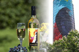 Bottle of wine with a glass with a popsilos in the background and flowers