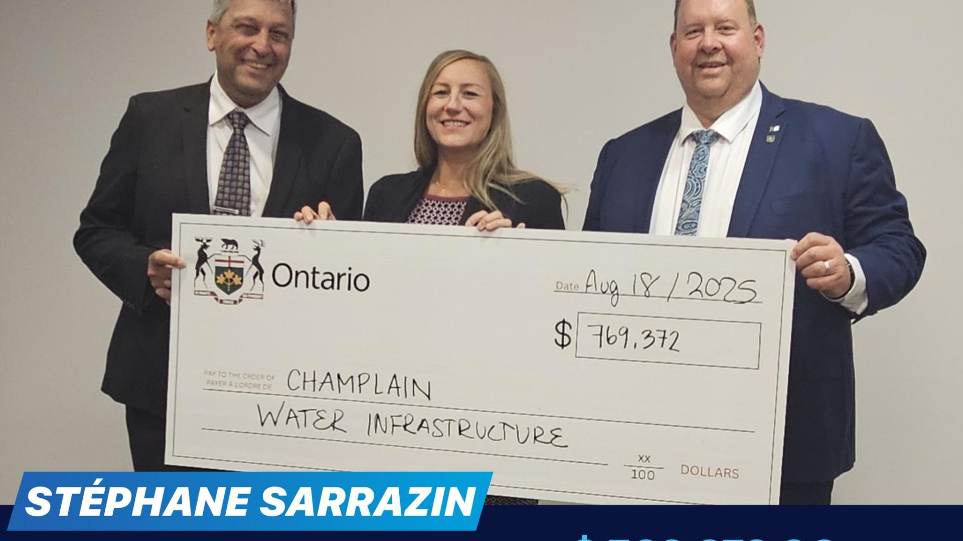 Three people smiling, holding a large cheque for Champlain Water Infrastructure.