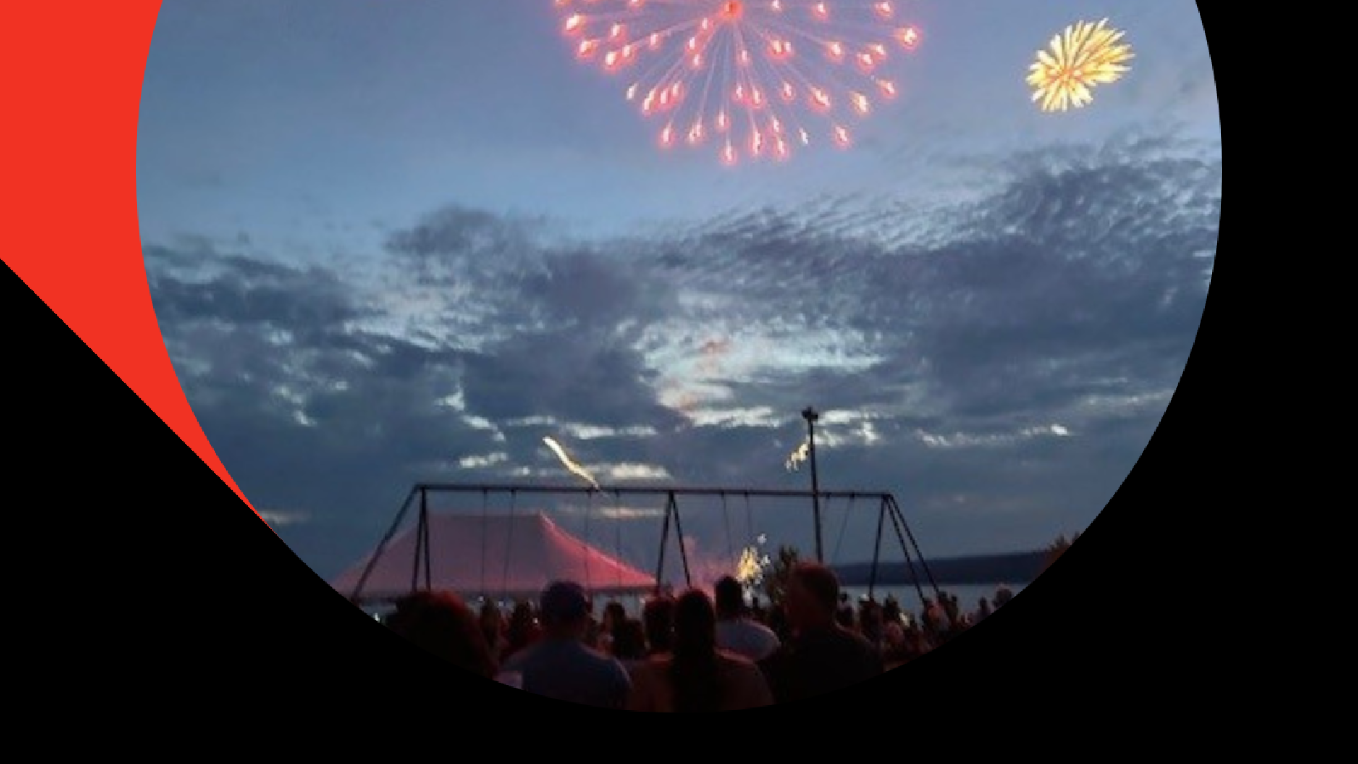 Fireworks light up the evening sky over a silhouetted crowd.