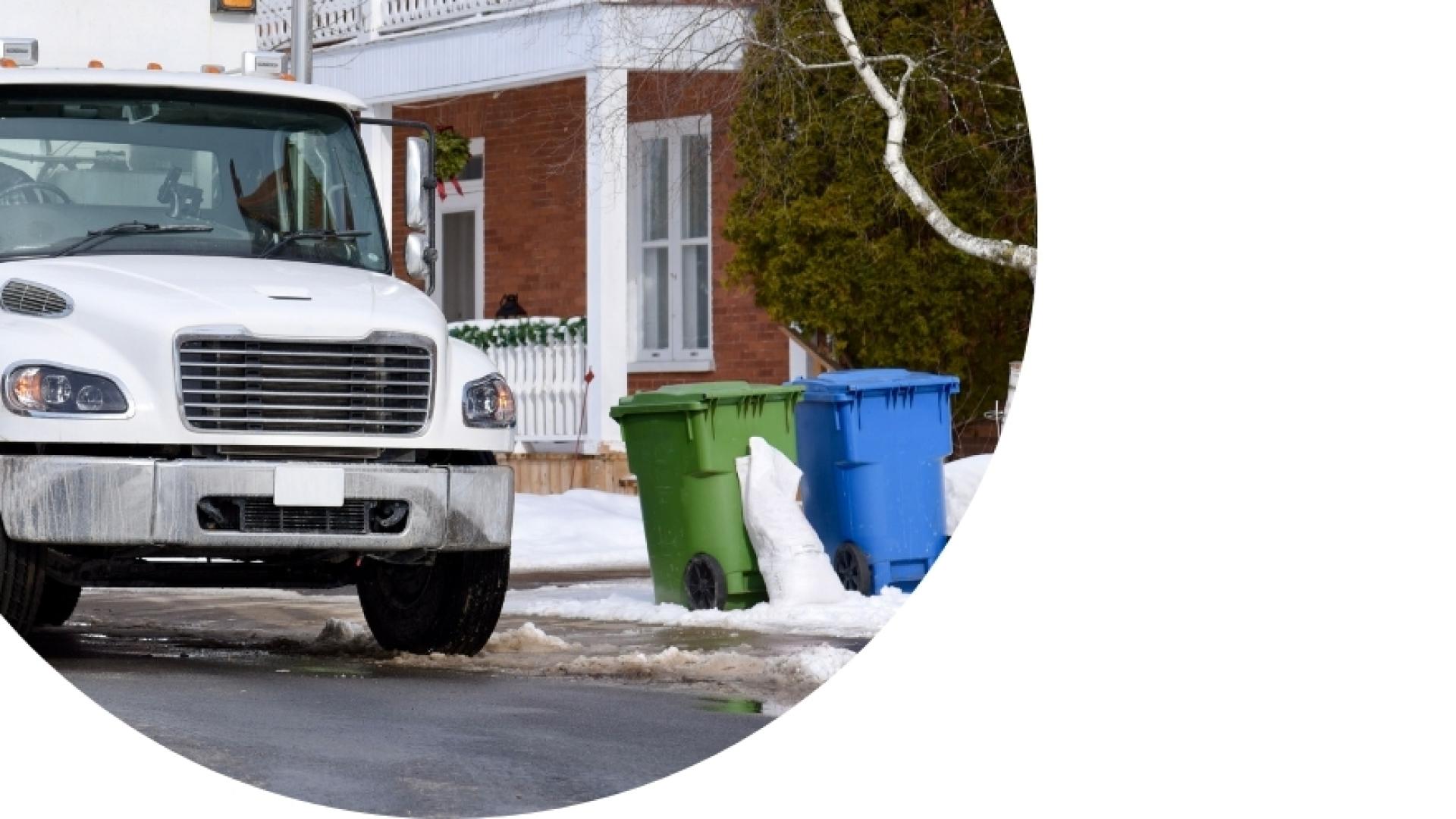 garbage truck driving towards green and blue bins