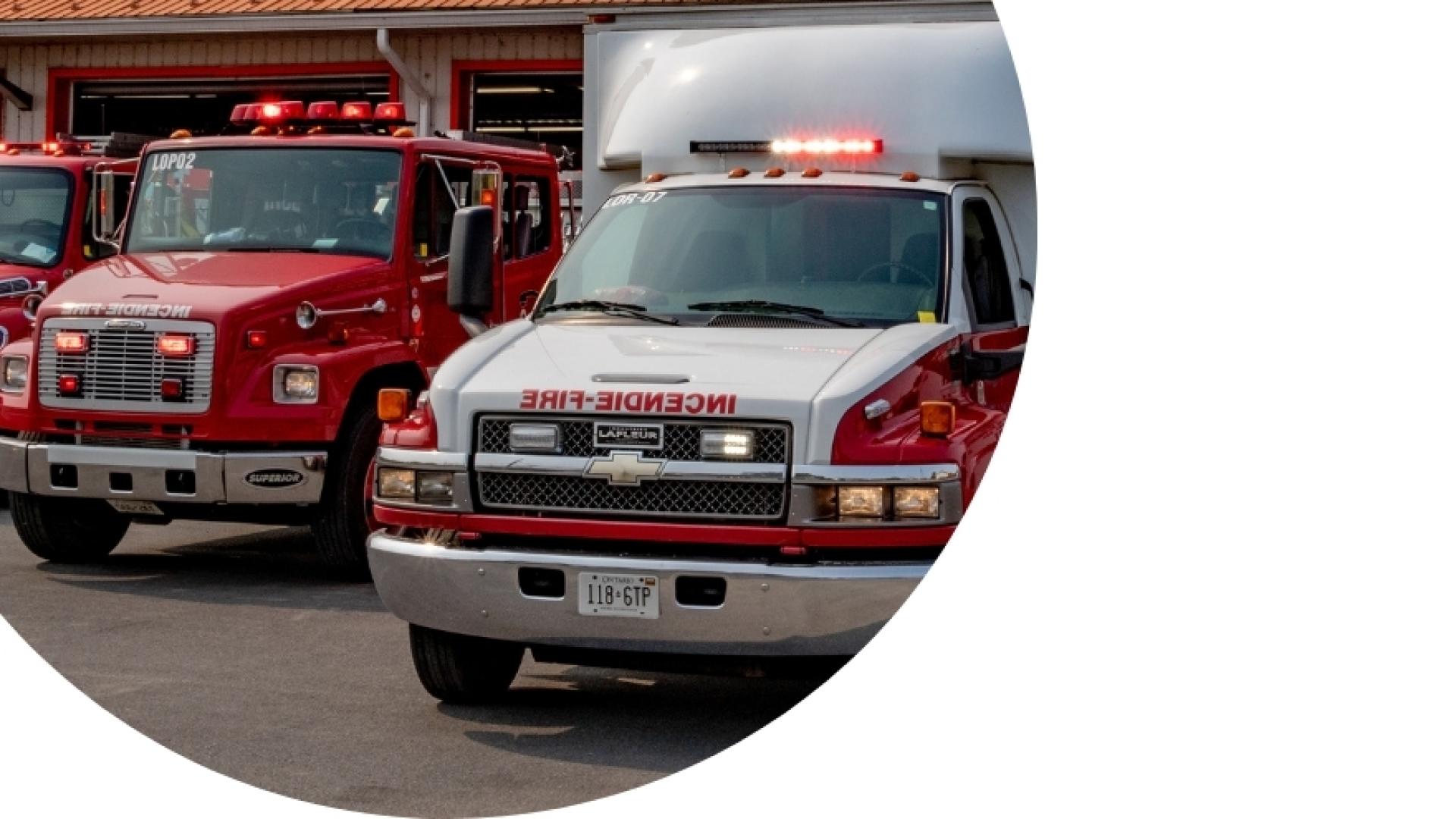 ambulance with 2 firetrucks in front of a firehouse