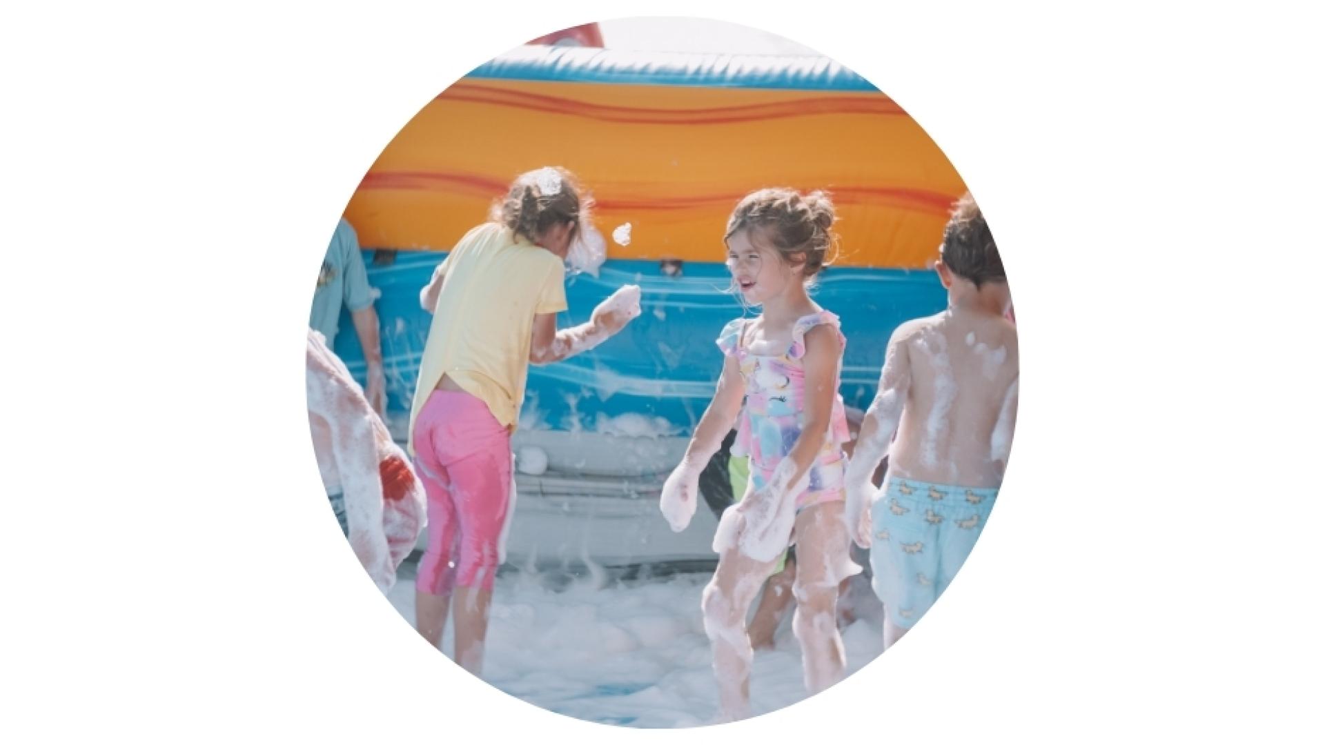 kids playing in a foam inflatable pool during a sunny day