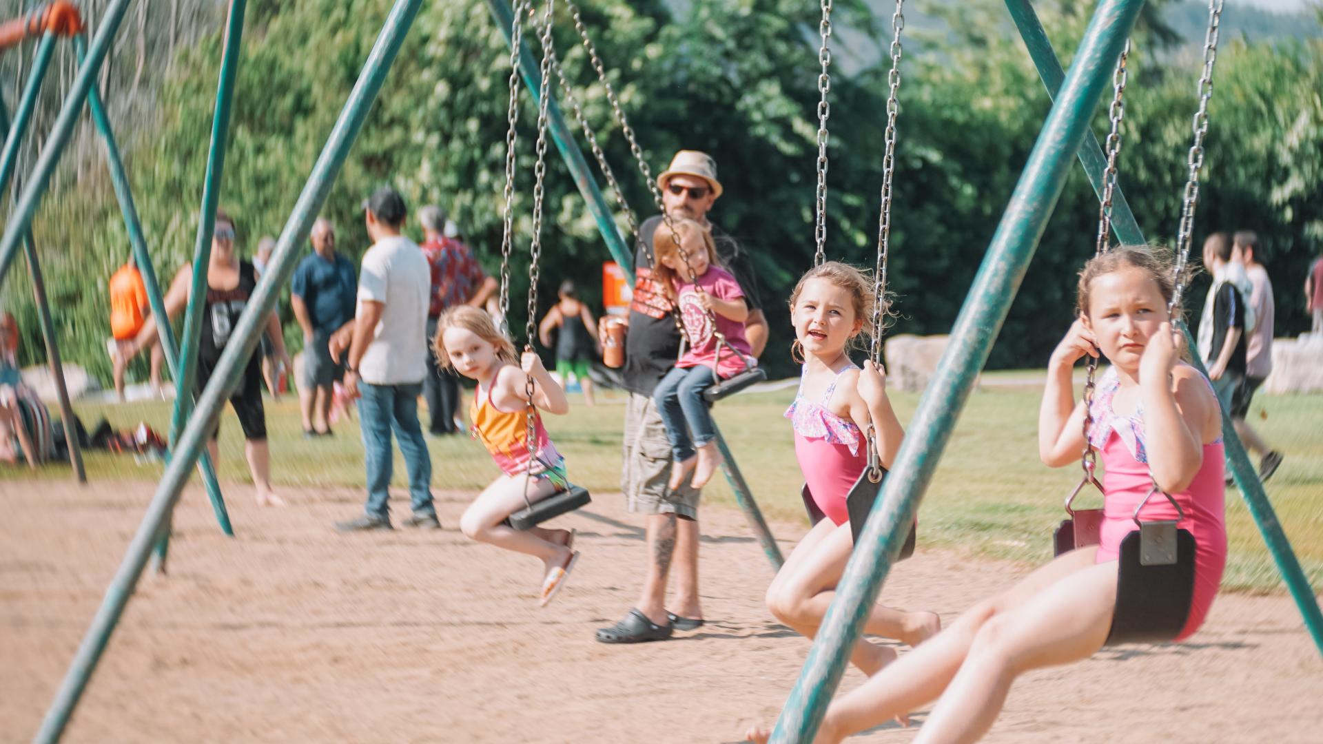 Children playing on swings at L’Orignal Beach park during a community Canada Day event.