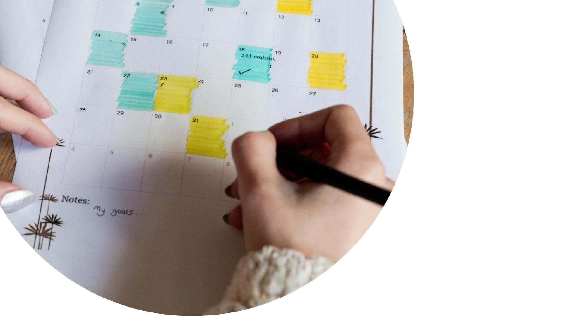 someone putting notes on a calendar with highlighted days