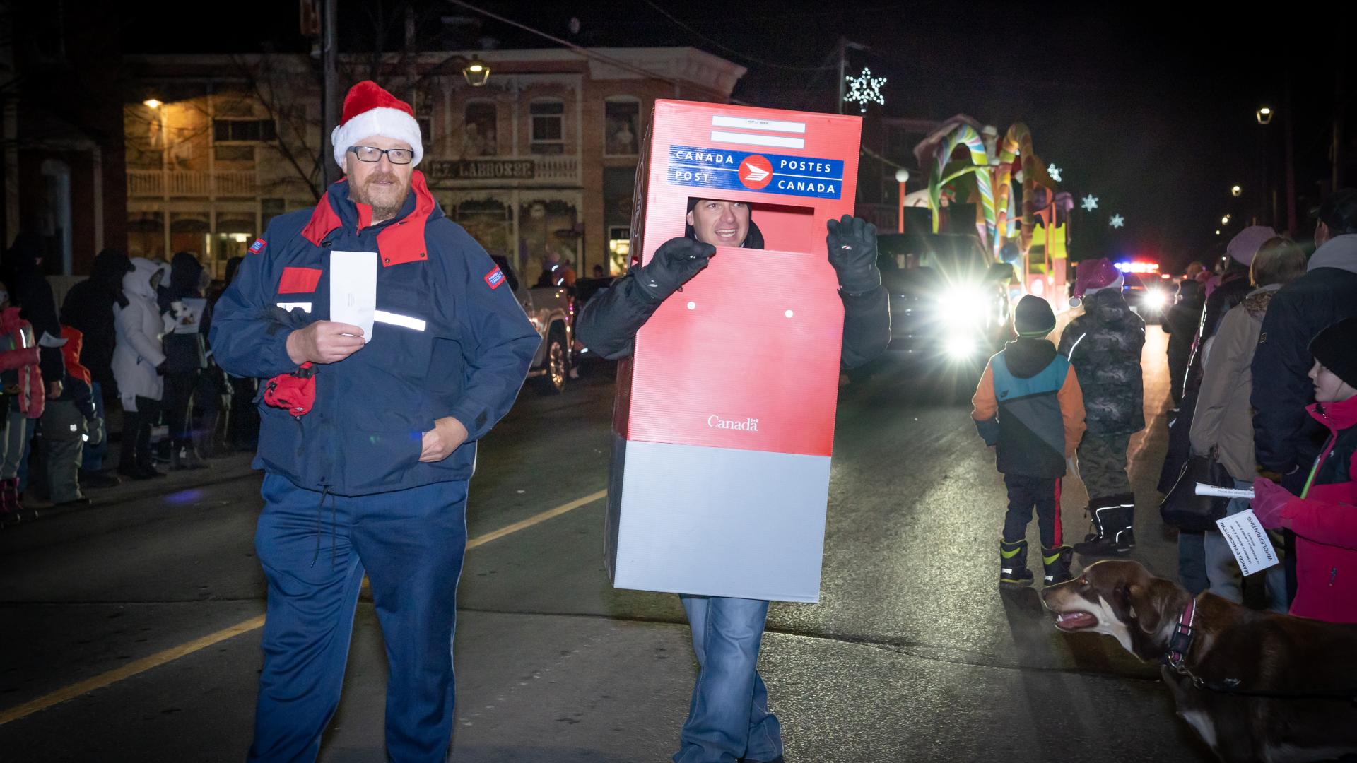 Canada Post volunteers walking in the Christmas parade collecting letters to Santa from children along the route.