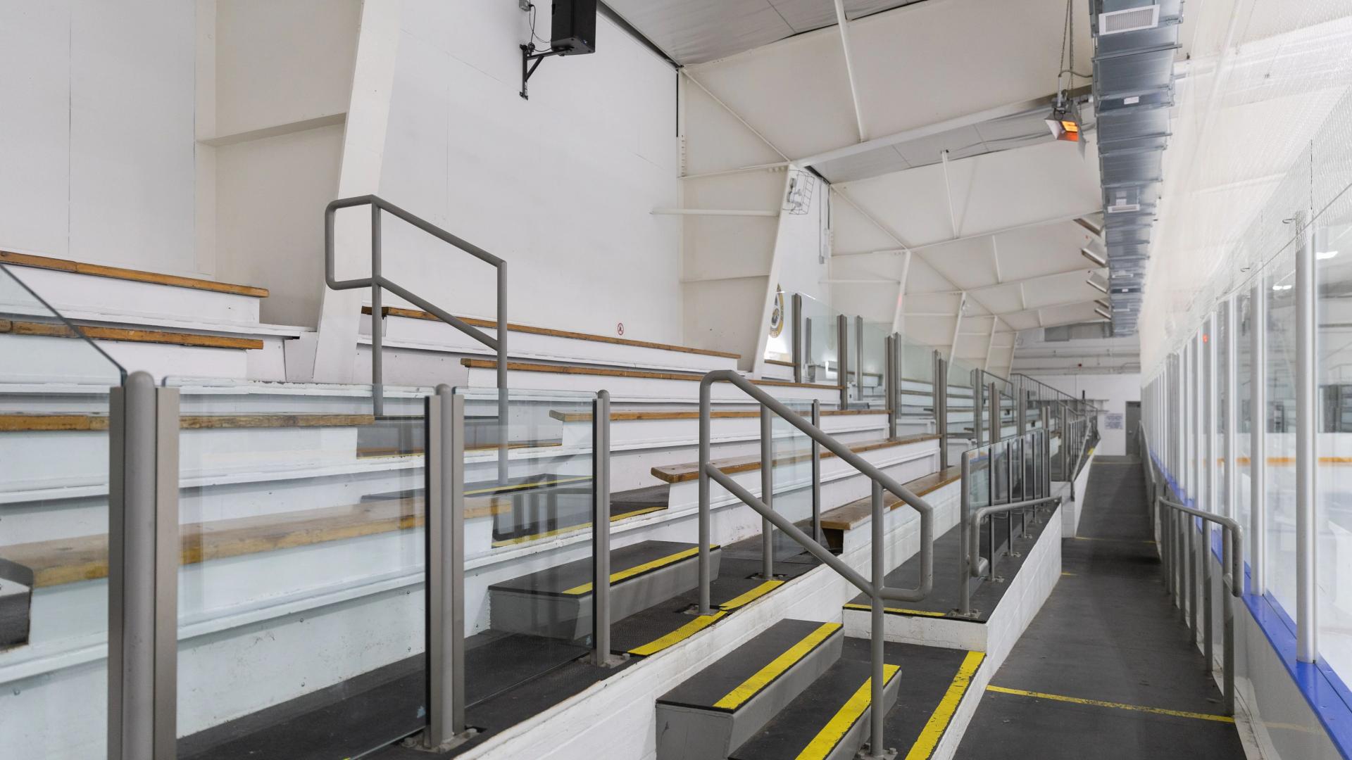 Interior view of the Vankleek Hill Arena showing spectator seating, accessible viewing areas, and the ice rink boards.