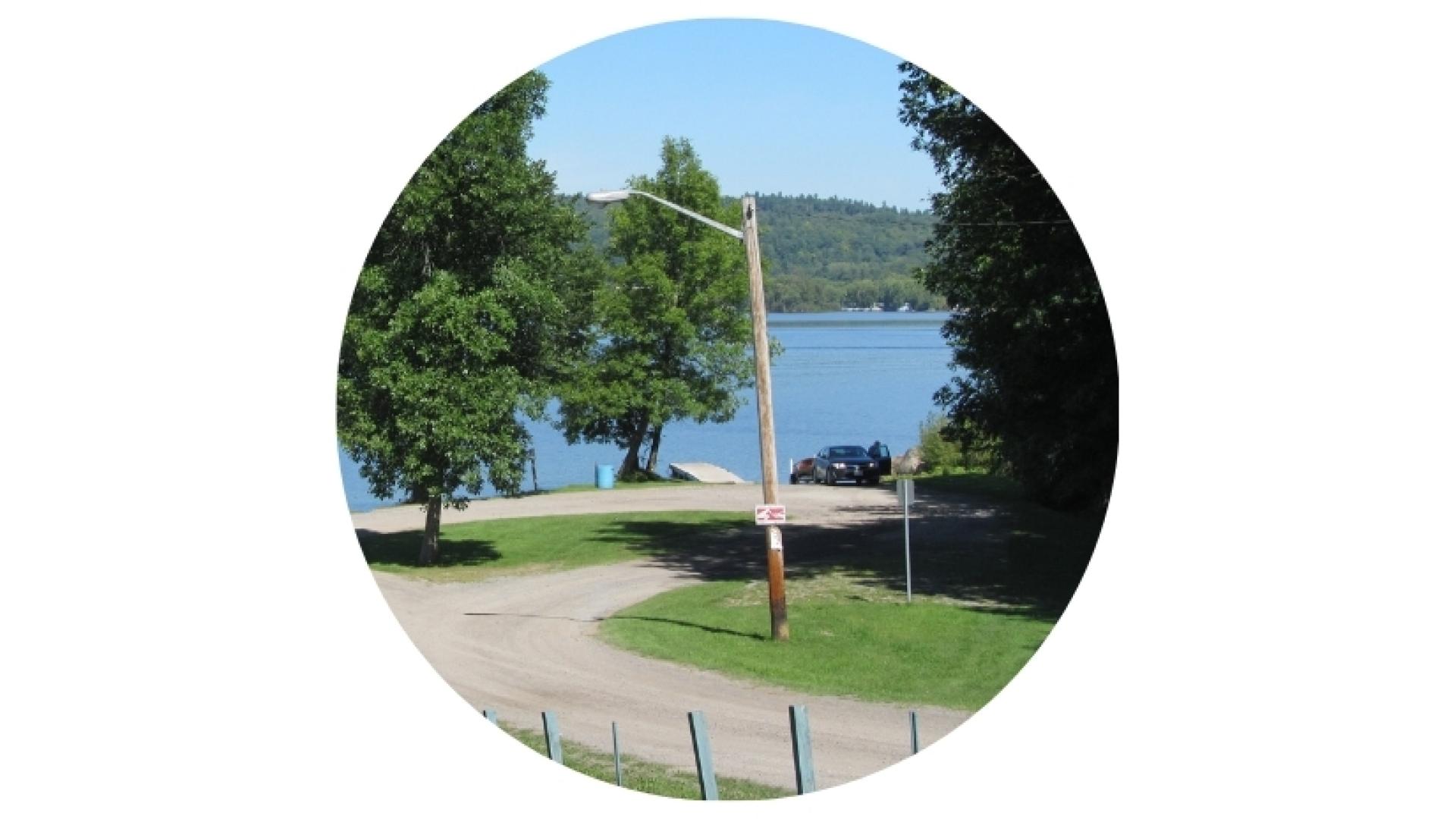 View of the L'Orignal Beach boat launch and dock leading into the Ottawa River, surrounded by trees and overlooking the waterfront.