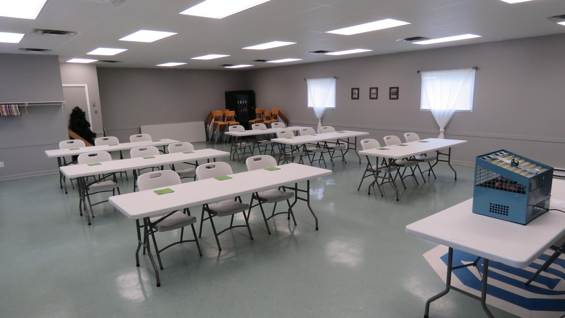 Community hall arranged with tables and chairs for a meeting, workshop, training session, or community gathering.
