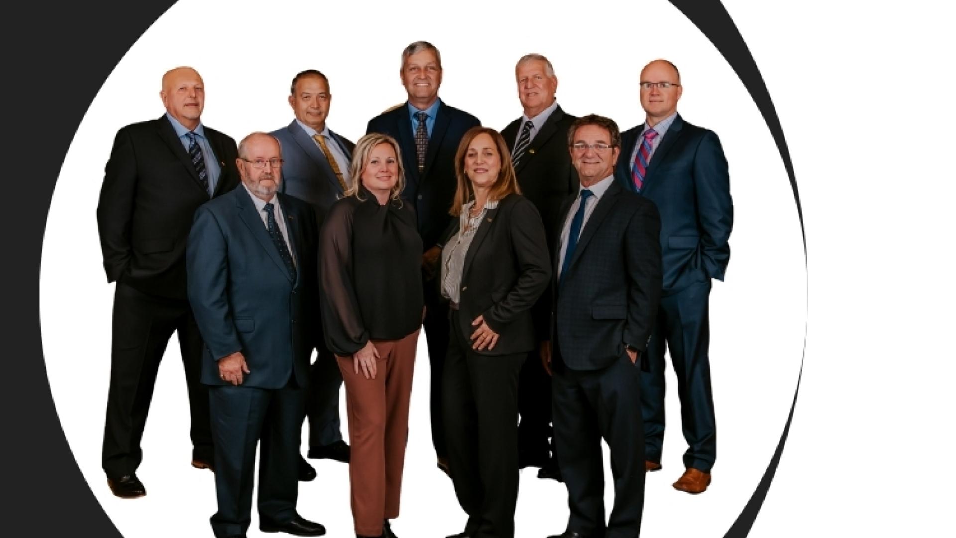 Group of nine people in formal attire on a dark background, Champlain logo above.