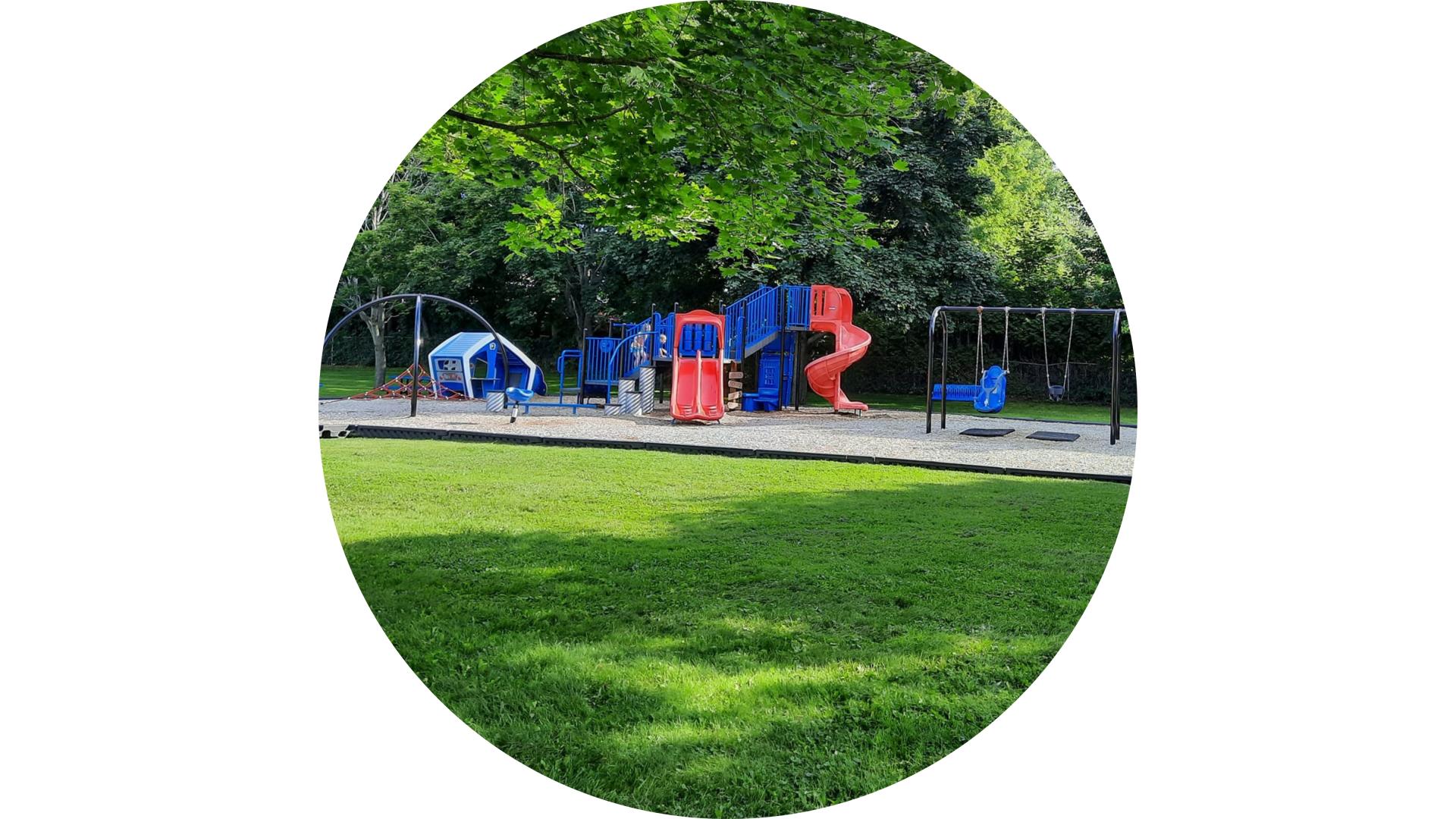 colourful playground surrounded by open green space and mature trees in a community park.