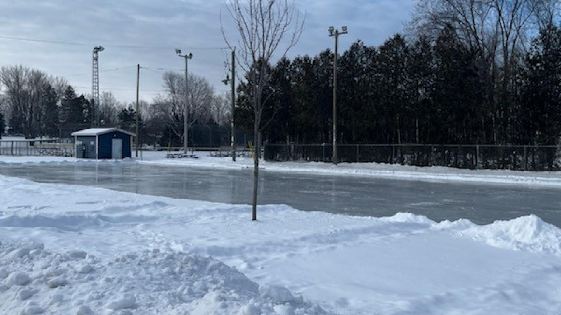 Snow-covered outdoor skating rink surrounded by trees