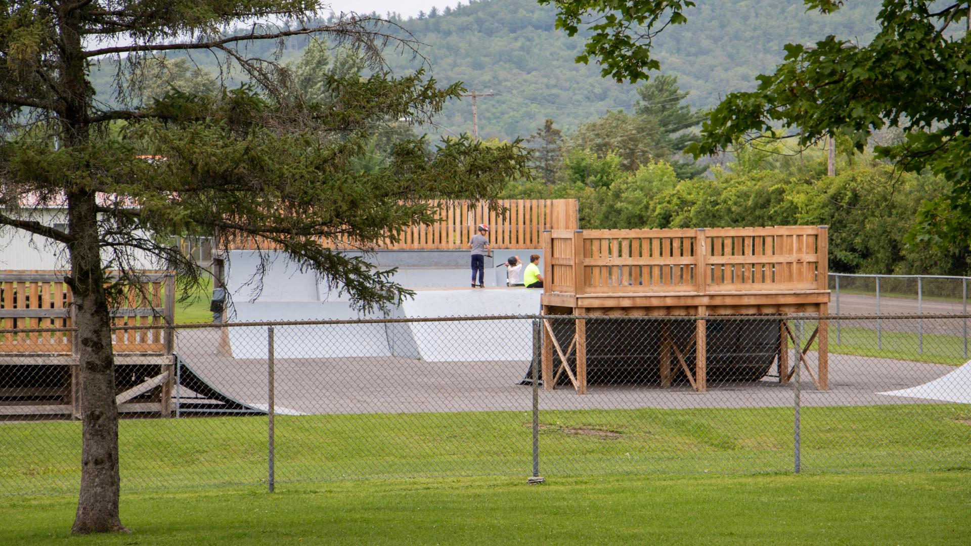 Outdoor skatepark featuring ramps and platforms, surrounded by green space and trees in L'Orignal Park.