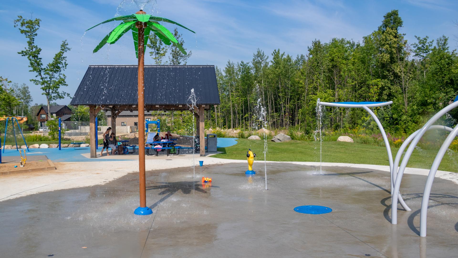 Accessible splash pad featuring interactive water play elements, spray arches, and open space for children to cool off and play.