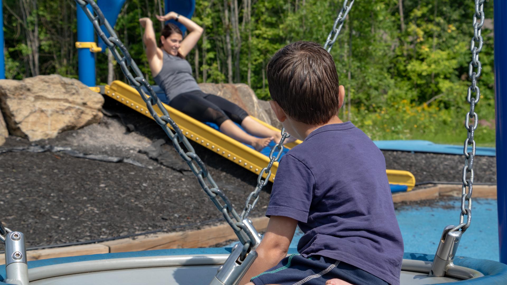 Children using an accessible playground swing designed for inclusive play at Sacha's Park.