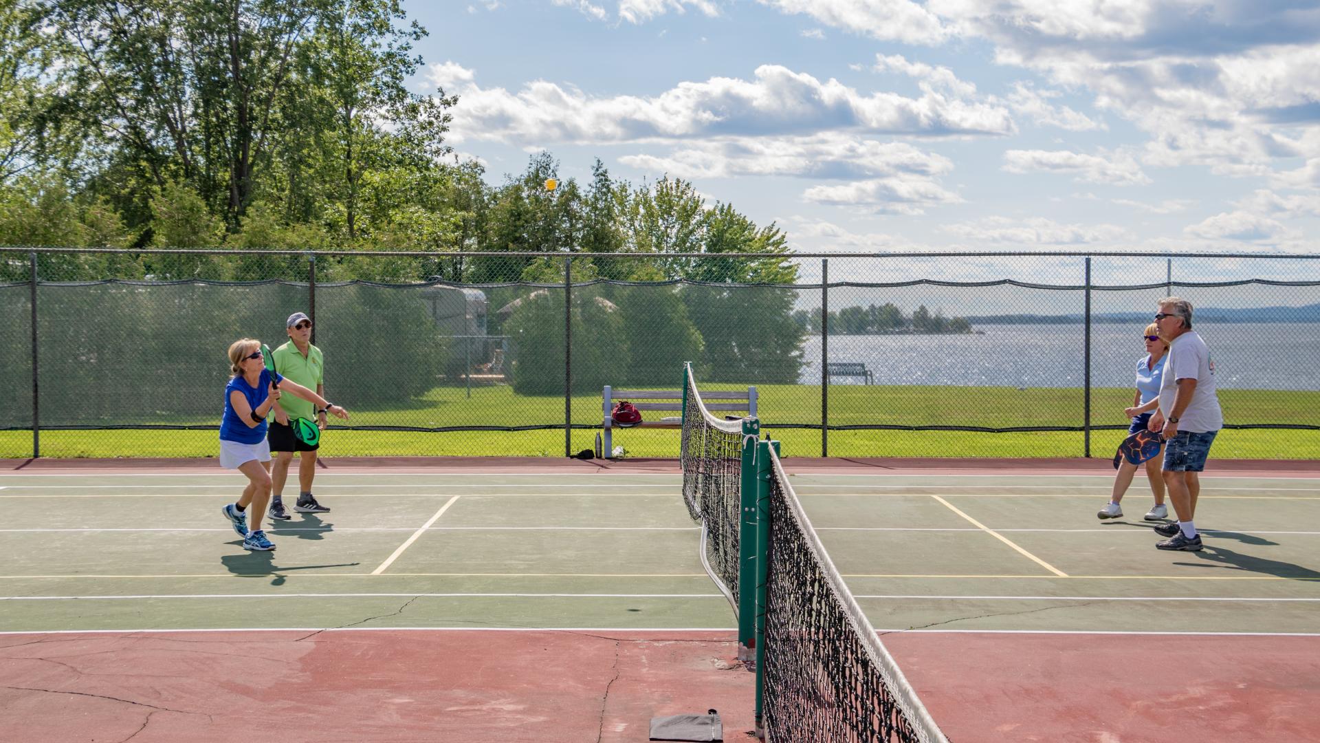 Four seniors playing pickleball with the river in the background.