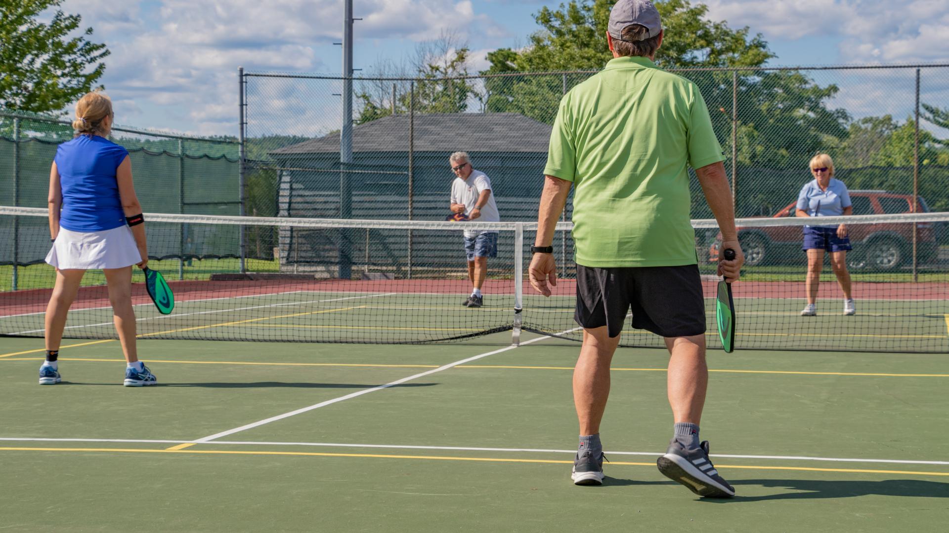 People playing pickleball on outdoor courts, enjoying a recreational game on a sunny day.