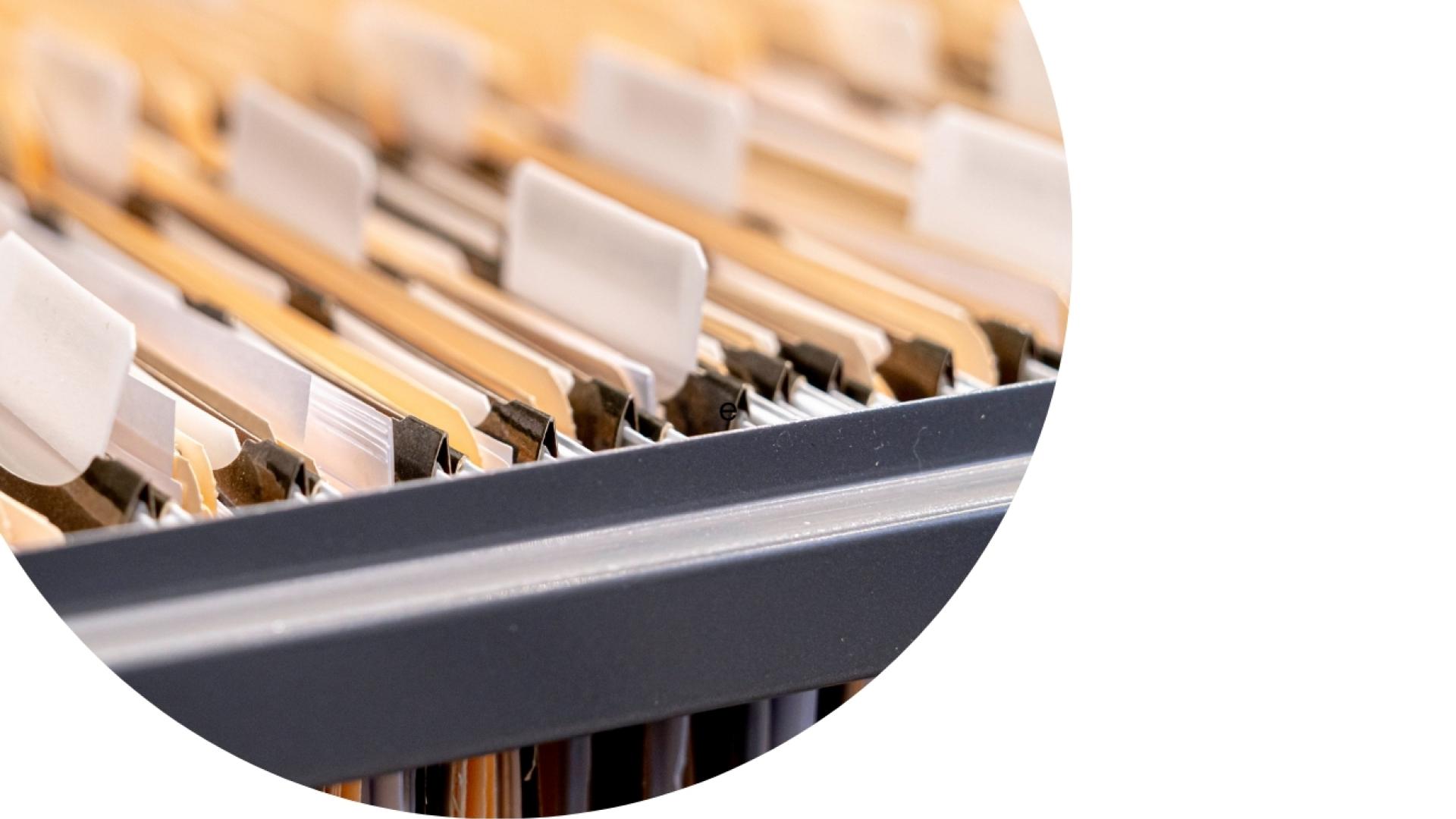 Open filing cabinet drawer containing organized hanging file folders and labeled document files