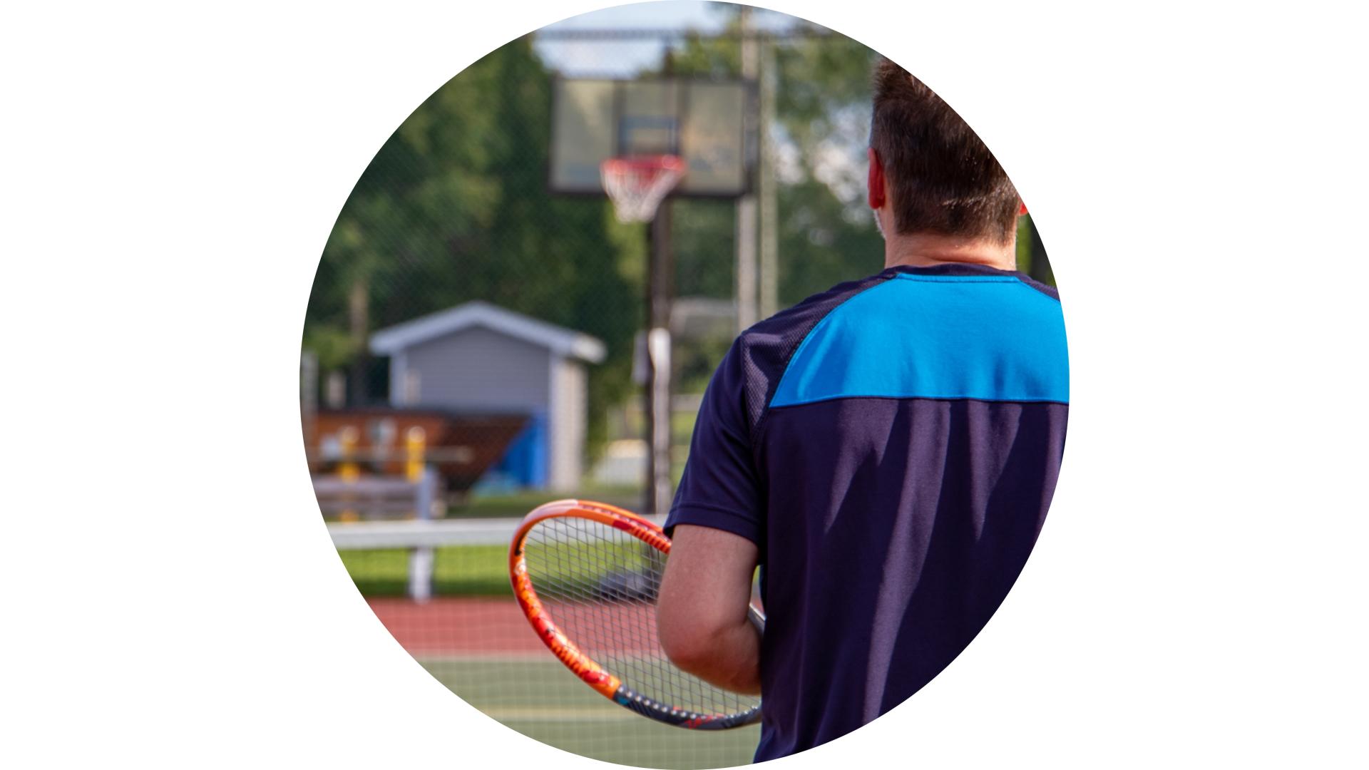 Person standing in a tennis court waiting to receive the ball.