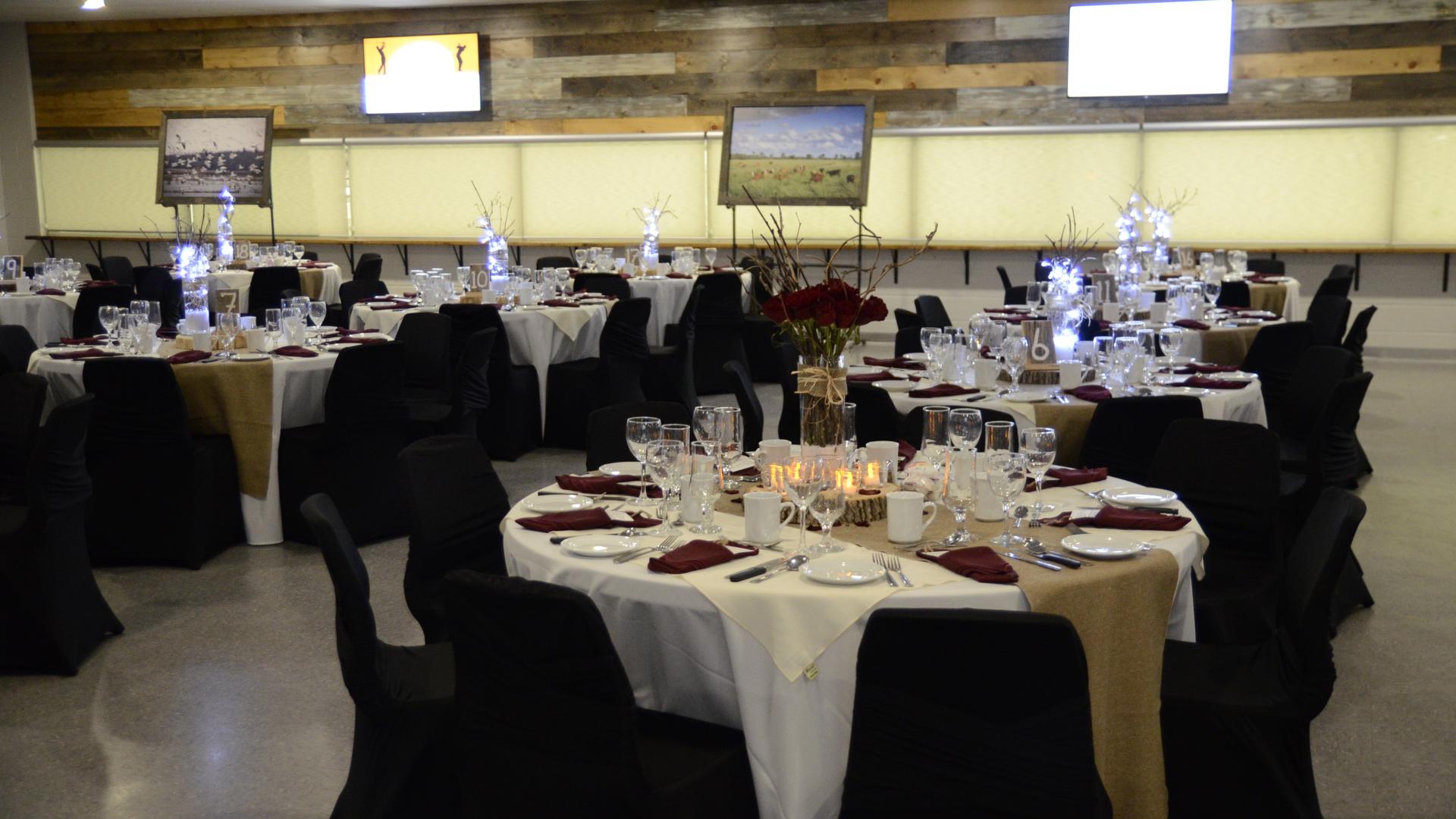 Round tables set for a banquet in a community hall, with guests seated and dining during a formal event.