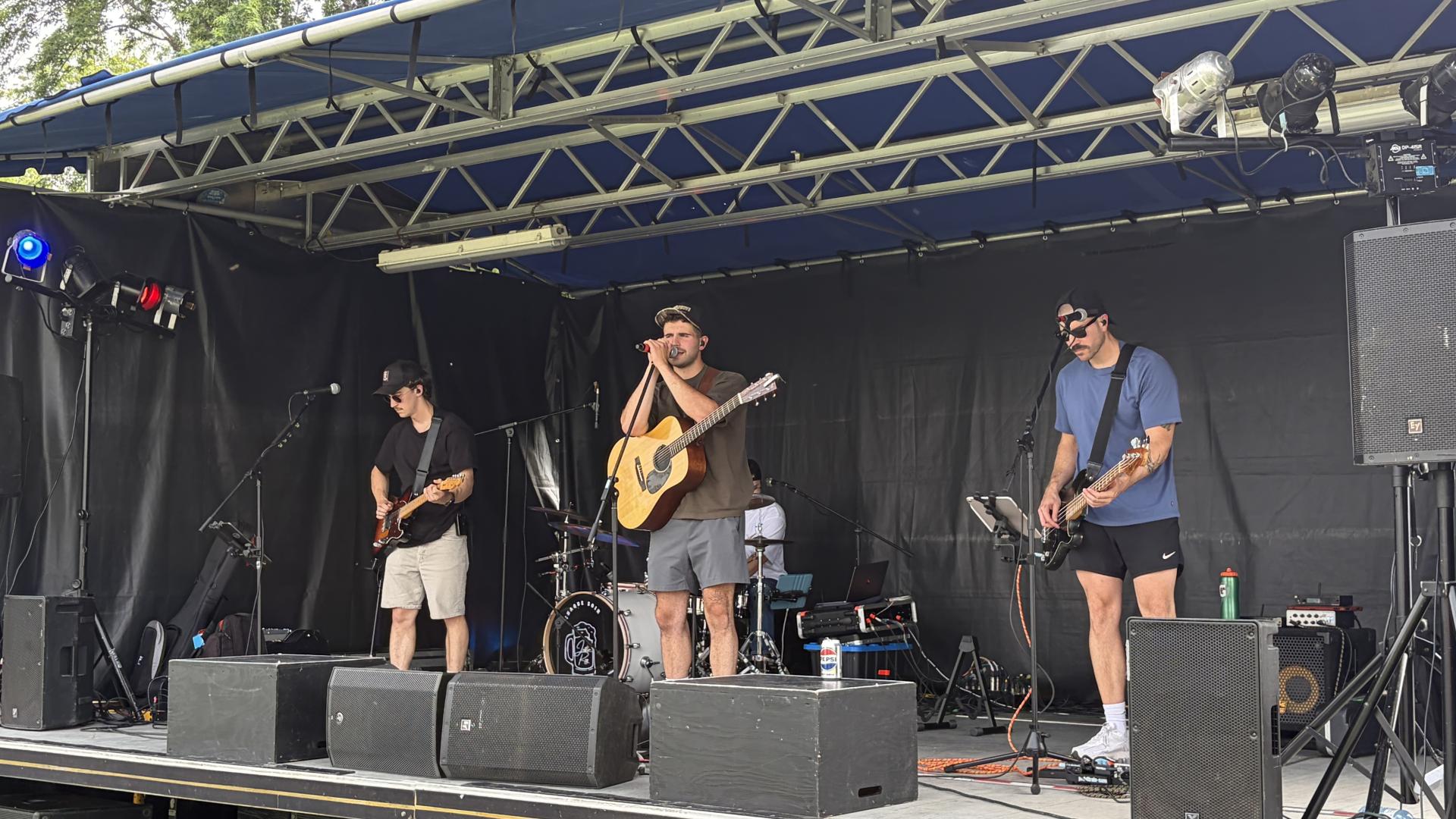 Band performing on an outdoor stage during the Canada Day celebrations, with lead singer Justin Roy playing guitar and singing while other musicians perform under stage lighting.