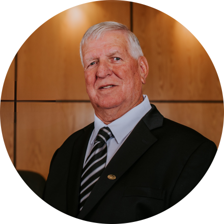 A person in a suit stands smiling in a wood-panelled office setting.