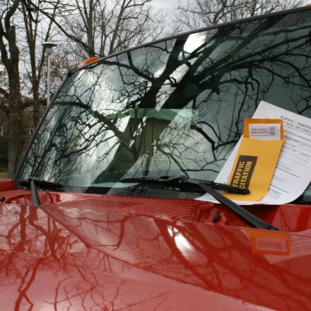 a red truck with a parking ticket in its windshield 
