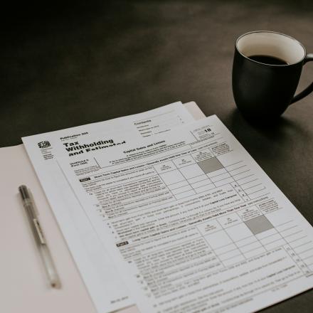 documents in a folder on a desk with pen and coffee
