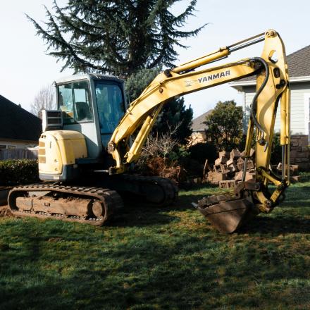 a yellow excavator about to dig a yard