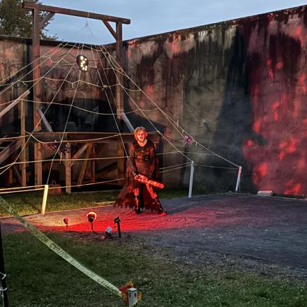 Spooky person in costume standing beneath a giant spider web structure in a dark court jail