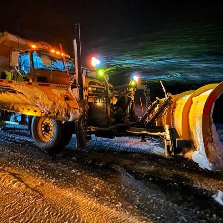 yellow snowplow on a wintery road during the night