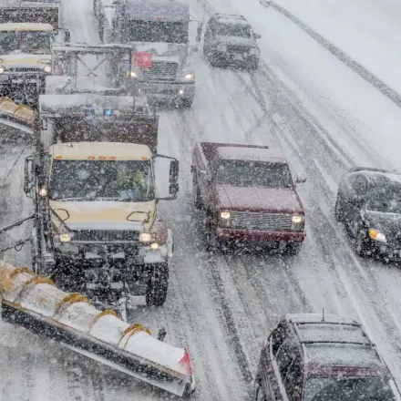 snowplows on a road full of traffic during winter