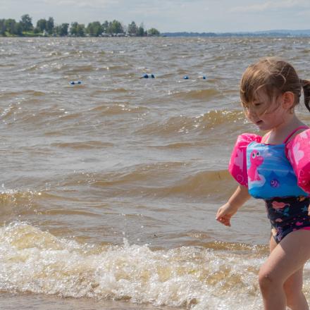 little girl playing in the water at the beach with bouy in the background.
