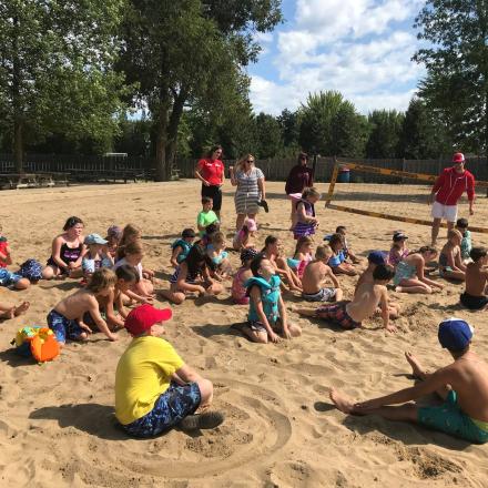 kids sitting on the sand on a beach with teenagers animators around them