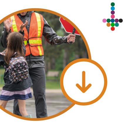 A school crossing guard in a reflective safety vest helping a child cross the street, shown inside an orange circular frame.