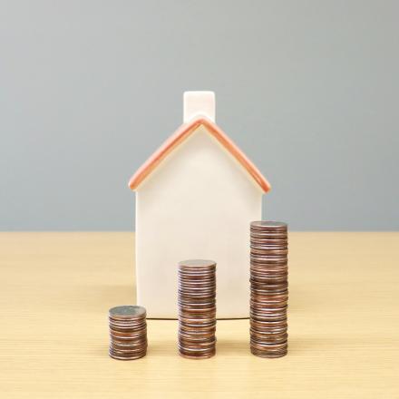 Small house model beside stacks of coins representing property taxes.