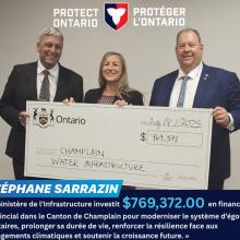 Trois personnes souriantes tenant un chèque géant.