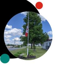 Canadian flag flying on a flagpole beside a roadway, framed within a black and teal graphic design.