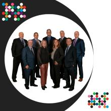 Group of nine people in formal attire on a dark background, Champlain logo above.