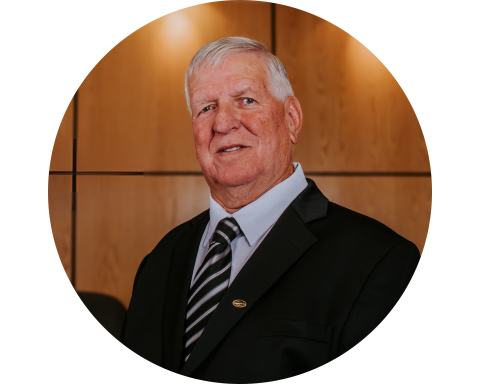 A person in a suit stands smiling in a wood-panelled office setting.
