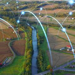Aerial view of farmland with digital connectivity arcs overhead.