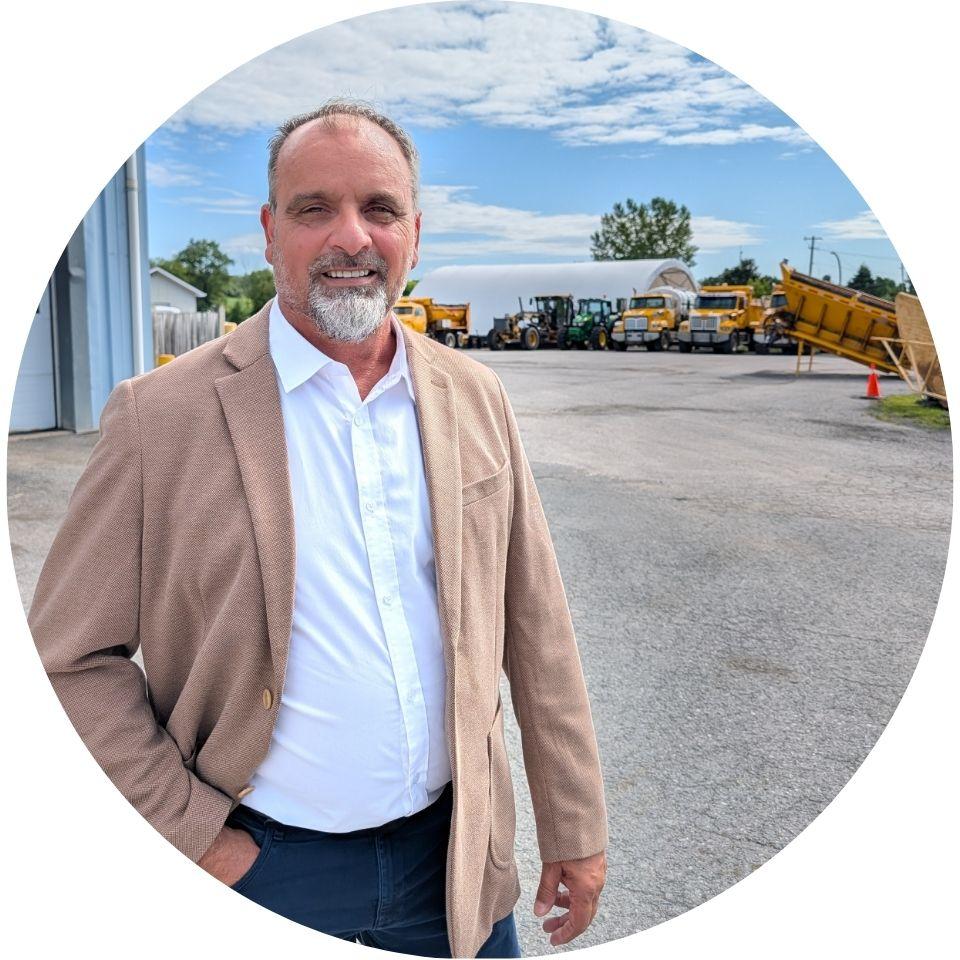Men standing outside a commercial building near a parking lot and construction equipment.